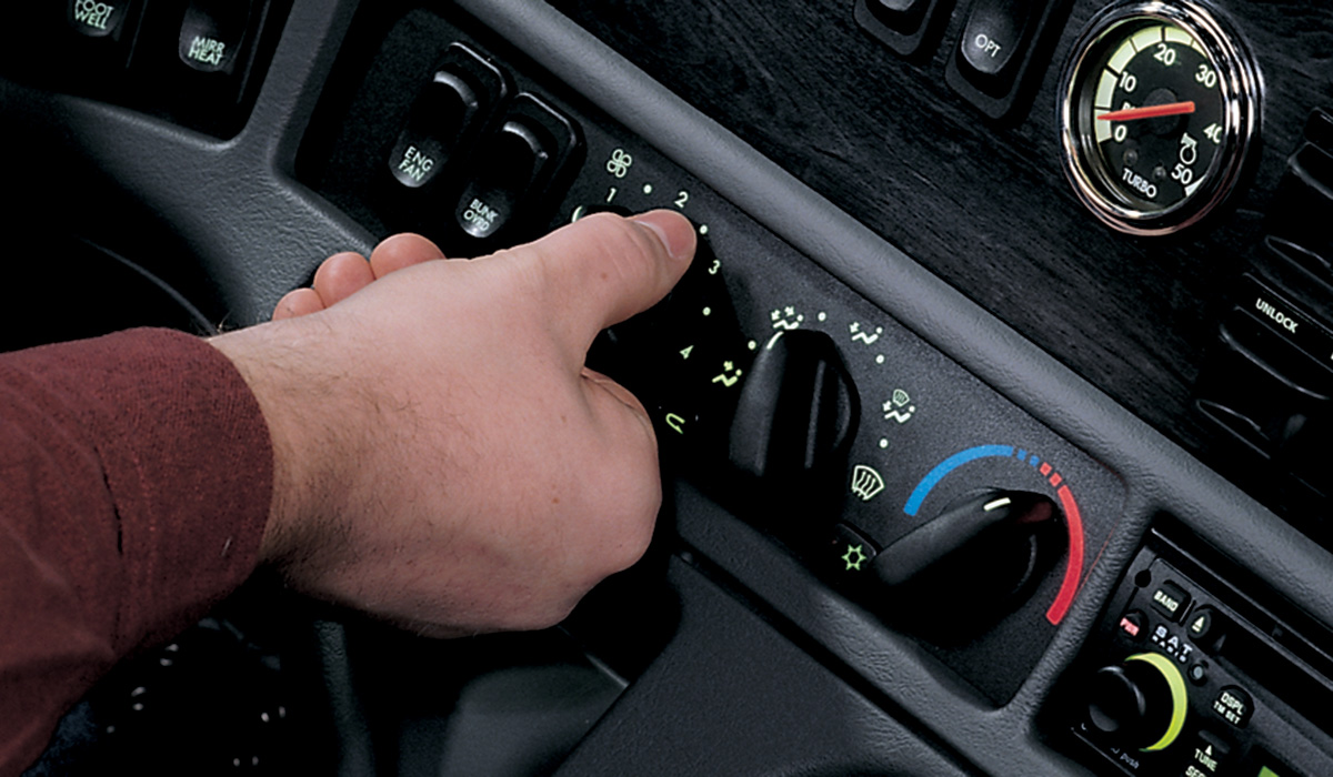 Photo of hand setting climate control dials on truck dashboard.